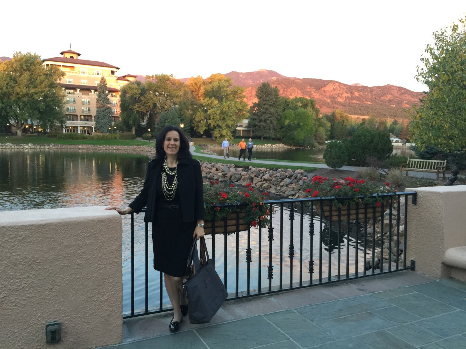 Asta Sanders standing outdoors near a lake with mountains in the background